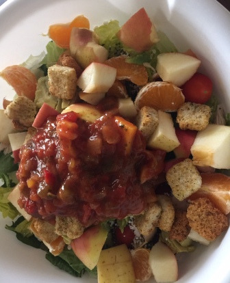 This salad included: romaine lettuce, an apple, two clementines, avocado, feta cheese, cherry tomatoes, croutons, chia seeds, chicken, and mango salsa.